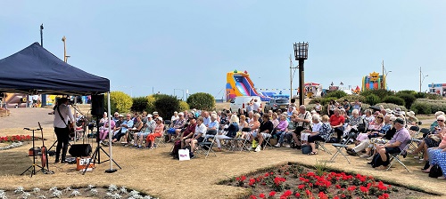 People sitting outside by the beach listening to music