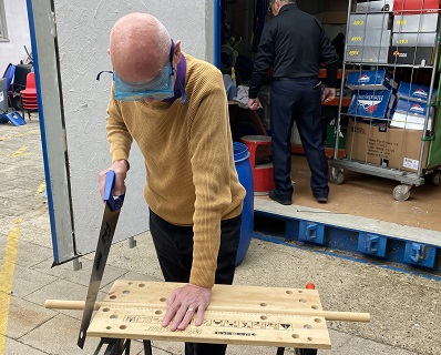 A person sawing wood outside the shed