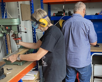 Two people working using tools in the shed