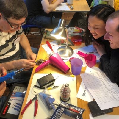 Group of people sitting at a table looking at an electrical activity